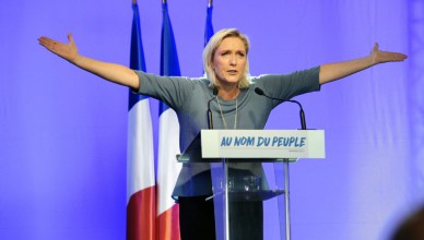 TOPSHOT - French far-right Front National (FN) party's President, Marine Le Pen, gestures as she delivers a speech on stage during the FN's summer congress in Frejus, southern France, on September 18, 2016. 
Marine Le Pen's slogan reading "In the name of the [French] people" is seen on the rostrum. / AFP / Franck PENNANT        (Photo credit should read FRANCK PENNANT/AFP/Getty Images)