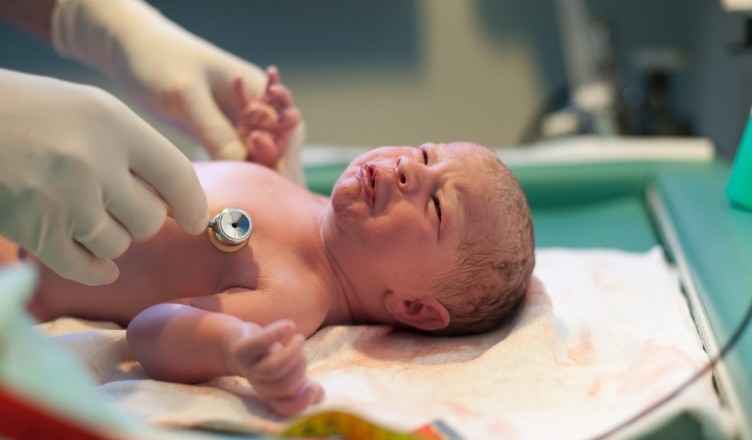 Newborn baby being examined in delivery room by doctor