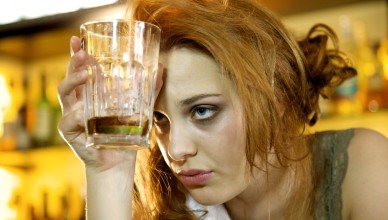 Young woman with a hangover holding her almost empty cocktail glass