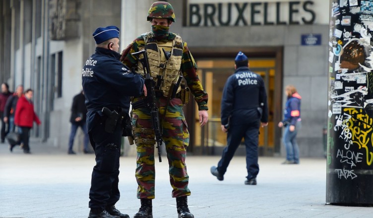 TOPSHOT - A Belgian soldier speaks to a police officer outside Brussels Central Station as people are allowed in small groups of ten to reach the station in order to take their commuter train following attacks in Brussels on March 22, 2016. 
Airlines cancelled hundreds of flights and European railways froze links with Brussels after a series of bombs blasts killed around 35 people in the city's airport and a metro train, sparking a broad security response. / AFP / EMMANUEL DUNAND        (Photo credit should read EMMANUEL DUNAND/AFP/Getty Images)