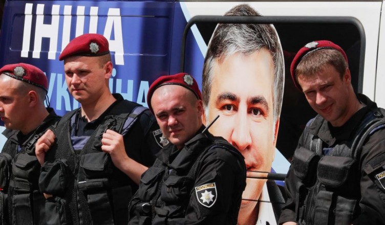 epa05999099 Ukrainian policemen stand next to a car with portrait of the former regional governor in the southern-Ukrainian city of Odessa and former Georgian president Mikhail Saakashvili during a rally of his supporters near of the Justice Ministry in Kiev, Ukraine, 30 May 2017.  Protesters gathered to demand registration of the Mikhail Saakashvili political party 'The movement of new strengths' and dismiss registration of the fake party with the same name reading like 'The block of Mikhail Saakashvili', which was allegedly registered by Oleg Sushko, according to local media reports.  EPA/SERGEY DOLZHENKO
