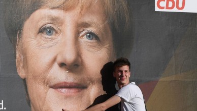 3198262 09/22/2017 A man stands by a poster featuring German Chancellor Angela Merkel, leader of the Christian Democratic Union, is seen here on a Berlin street on the eve of the German federal election. Grigoriy Sisoev/Sputnik