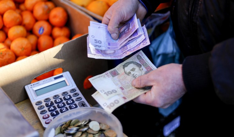 A market trader counts out hryvnia currency banknotes at a fruit stall in Kiev, Ukraine, on Monday, Feb. 3, 2014. Ukraine's opposition got a boost in its struggle to wrest power from President Viktor Yanukovych as a report said the European Union and U.S. are working on an aid package to rival assistance from Russia. Photographer: Vincent Mundy/Bloomberg