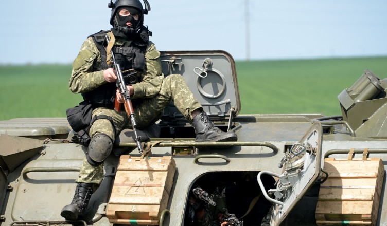 A member of the Ukrainian special forces takes position atop an armoured personnel carrier (APC) in the eastern Ukrainian city of Slavyansk on April 24, 2014. Ukraine's military launched an assault on the flashpoint rebel-held town of Slavyansk, sending in armoured vehicles and a helicopter, AFP journalists in the town reported. Several armoured personnel carriers drove past an abandoned rebel roadblock in flames to take up position at the entry to the town. AFP PHOTO/KIRILL KUDRYAVTSEV