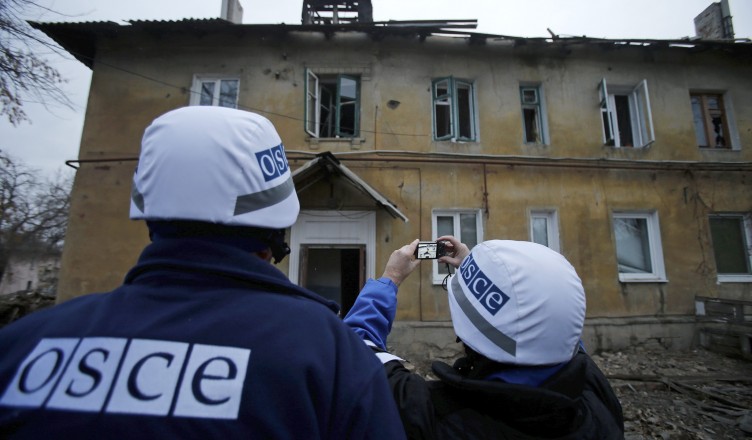 An Organization for Security and Cooperation in Europe (OSCE) investigator takes pictures of a building after it was damaged by recent shelling in the western part of Donetsk, eastern Ukraine, November 27, 2014. REUTERS/Antonio Bronic (UKRAINE  - Tags: CONFLICT CIVIL UNREST)
