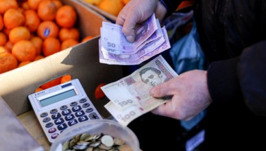 A market trader counts out hryvnia currency banknotes at a fruit stall in Kiev, Ukraine, on Monday, Feb. 3, 2014. Ukraine's opposition got a boost in its struggle to wrest power from President Viktor Yanukovych as a report said the European Union and U.S. are working on an aid package to rival assistance from Russia. Photographer: Vincent Mundy/Bloomberg