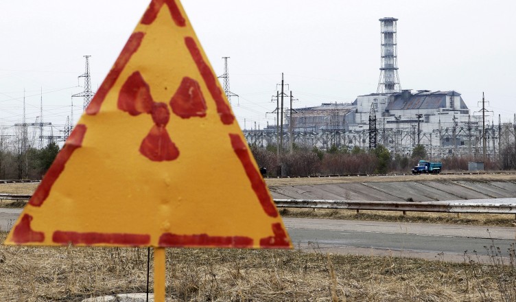 A radiation sign is seen, with a sarcophagus covering the damaged fourth reactor at the Chernobyl nuclear power plant in the background, April 4, 2011. Belarus, Ukraine and Russia will mark the 25th anniversary of the nuclear reactor explosion in Chernobyl, the place where the world's worst civil nuclear accident took place, on April 26. Engineers are still struggling to regain control of damaged reactors at the Fuskushima plant after last month's earthquake and tsunami, in the worst nuclear crisis since Chernobyl in 1986, with the government urging the operator of the plant to act faster to stop radiation spreading.   REUTERS/Gleb Garanich  (UKRAINE - Tags: ANNIVERSARY DISASTER ENERGY ENVIRONMENT) - RTR2KTBP