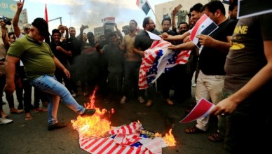 Supporters of Iraqi Shi'ite cleric Moqtada al-Sadr burn a U.S flag during a protest against western air strikes on Syria, at Tahrir Square in Baghdad, Iraq April 15, 2018. REUTERS/Thaier Al-Sudani