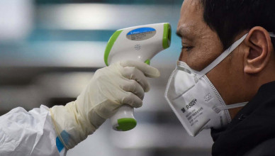 A medical staff member takes the temperature of a man at the Wuhan Red Cross Hospital in China on Jan. 25. HECTOR RETAMAL/AFP via Getty Images