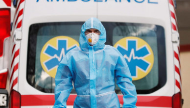 A medical worker wearing protective gear stands next to an ambulance outside a hospital for patients infected with the coronavirus disease (COVID-19) in Kyiv, Ukraine November 24, 2020.  REUTERS/Gleb Garanich