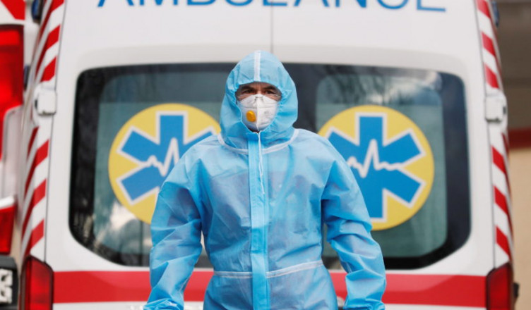 A medical worker wearing protective gear stands next to an ambulance outside a hospital for patients infected with the coronavirus disease (COVID-19) in Kyiv, Ukraine November 24, 2020.  REUTERS/Gleb Garanich