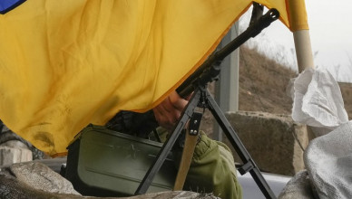 A machine gun emerges from under a Ukrainian national flag on a front line position near Kharkiv, Ukraine, Saturday, March 26, 2022. (AP Photo/Efrem Lukatsky)