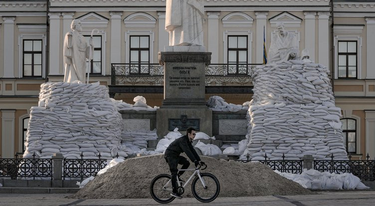 A man rides a bicycle backdropped by a statue of Grand Princess Olga of Kyiv, in the process of being covered in sandbags to avoid damage from potential shelling, in Kyiv, Ukraine, Monday, March 28, 2022. Ukraine is prepared to declare its neutrality and consider a compromise on contested areas in the country's east, President Volodymyr Zelenskyy said ahead of another round of talks set for Tuesday on stopping the fighting. (AP Photo/Vadim Ghirda)