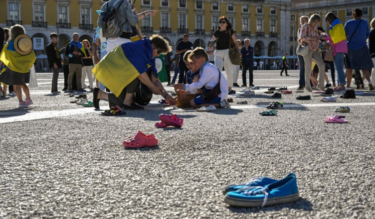 LISBON, PORTUGAL - JUNE 04: Ukrainians light candles during an action in which two hundred and forty pairs of children's shoes were on display in Praça do Comercio in memory of the prematurely killed Ukrainian children while demonstrators ask people to sign an electronic petition stating "Let's help stop the murders, crimes and atrocities committed by Russian soldiers against children in Ukraine," during "#SaveUkrainianChildren" civil action on June 04, 2022, in Lisbon, Portugal. Students from Ukrainian schools in Lisbon read poems and sung songs in support of Ukrainian children during the action. The aim of this international event, taking place in several cities, is to draw the attention of the international community, citizens and rulers to the plight of thousands of children in Ukraine. (Photo by Horacio Villalobos#Corbis/Corbis via Getty Images)