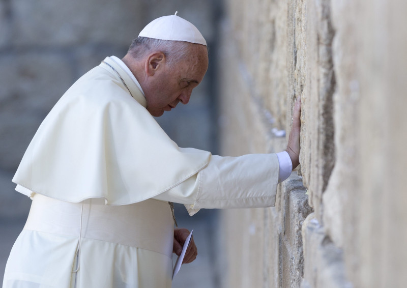 epa04225978 Pope Francis bows his head and touches the stones of the Western Wall, Judaism's holiest site, before placing a note into the crevices, in Jerusalem, Israel, 26 May 2014. Pope Francis prayed at the Western Wall, the only standing remnant of the platform that once housed the Jewish Temple, in the Old City of Jerusalem amid heavy security. He placed his hand on the ancient stones and puts a note to God, as per Jewish tradition, between the cracks. The Pope is on an official visit Israel.  EPA/JIM HOLLANDER  Dostawca: PAP/EPA.