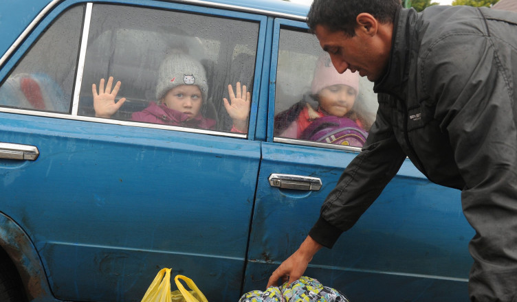 Children look through a car windows as they and other refugees from the Kharkov Region of Ukraine as they arrive at temporary camp in Belgorod, Russia, Wednesday, Sept. 14, 2022. Thousands fled fled northeastern Ukraine to Russia amid Ukrainian counteroffensive in the region. (AP Photo)