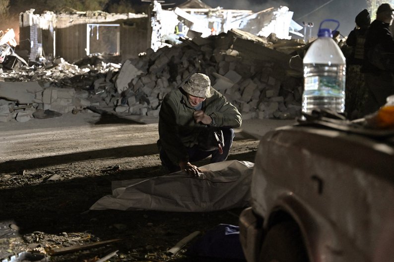 TOPSHOT - Local resident Sergiy mourns over the body of his spouse Svitlana who died in a Russian strike that destroyed a shop and a cafe in the village of Groza, some 30 kilometres west of Kupiansk, eastern Ukraine, on October 5, 2023. A Russian strike on October 5, 2023 killed at least 51 people gathered for a wake in an eastern Ukrainian village in what a UN official called a "horrifying" attack. Footage published by the Ukrainian police showed a large area of smoking rubble and several bodies being taken away by emergency workers in the village of Groza. Ukrainian President said the strike had slammed into the Kupiansk district of the war-battered region bordering Russia, where Moscow's forces have been pushing to recapture territory they lost last year to Ukrainian troops. (Photo by Genya SAVILOV / AFP) (Photo by GENYA SAVILOV/AFP via Getty Images)
