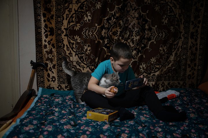 VYSOKOPILLYA, UKRAINE - DECEMBER 14: Ivan, 7, and his cat watch a cartoon on a smartphone at their home on December 14, 2023 in Vysokopillya, Ukraine. Both Russia and Ukraine's authorities deny targeting civilians in the nearly 22-month-long war that Russia launched against its neighbour in February 2022. Schools and education have been targeted by both sides, causing some parents to discontinue education to protect their children. (Photo by Gaelle Girbes/Getty Images)