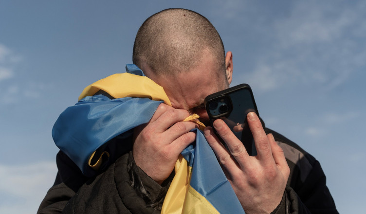 A recently swapped Ukrainian prisoner of war cries while calling his relatives after a prisoner exchange on the Ukrainian Russian border, on Wednesday, Jan. 31, 2024. Russia and Ukraine have exchanged about 200 prisoners of war each, the countries said Wednesday, despite tensions stemming from last week's crash of a military transport plane that Moscow claimed was carrying Ukrainian POWs and was shot down by Kyiv's forces. (AP Photo/Danylo Pavlov)
