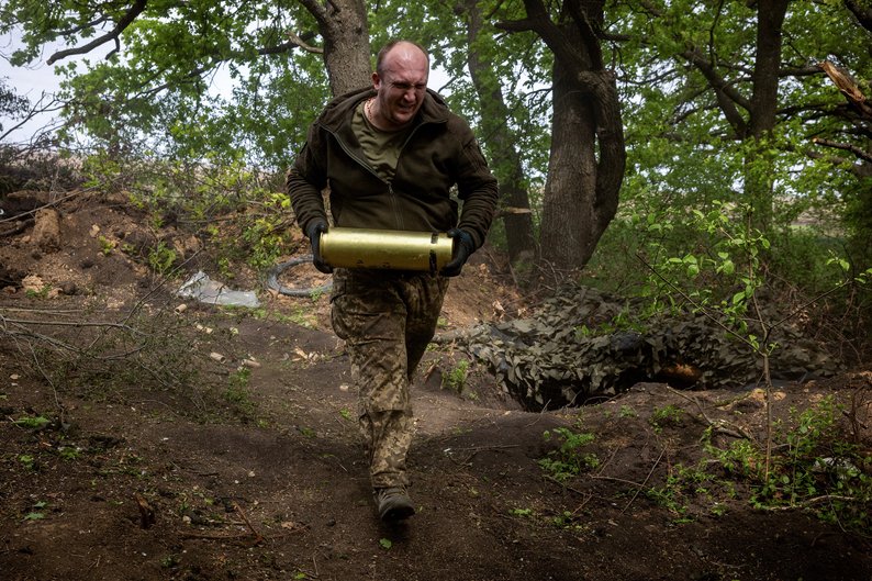 FILE PHOTO: A serviceman of Ukraine's 57th brigade carries an artillery shell at a position at the outskirts of Kupiansk, amid Russia's attack on Ukraine, April 21, 2024. REUTERS/Thomas Peter/File Photo