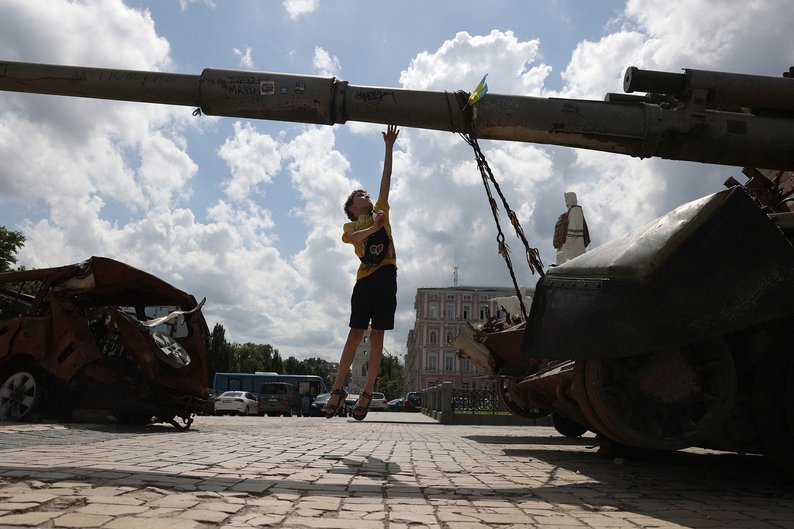 TOPSHOT - A boy jumps next to a destroyed Russian self-propelled gun on Mykhailivska Square in the center of Kyiv on June 11, 2024, amid the Russian invasion in Ukraine. (Photo by Anatolii STEPANOV / AFP) (Photo by ANATOLII STEPANOV/AFP via Getty Images)