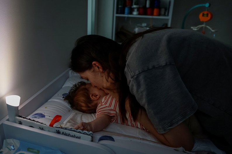 Maryna Tkalich, 33-year-old, kisses her 2-month-old baby after changing his clothes, during a blackout, amid Russia's attack on Ukraine, in Kyiv, Ukraine, June 7, 2024. REUTERS/Alina Smutko
