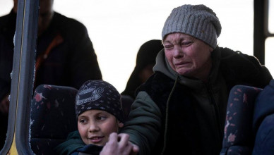 Mykolaivna Shankarukina, 54, leaving from the Ukrainian Red Cross, reacts while she says goodbye to her son as her grandson looks on, in Mykolaiv, southern Ukraine, on Monday, March 28, 2022. Shankarukina and her family evacuated from Sablagodante village at Mykolaiv district that have been attacked by the Russian army. She and her grandson go to Odesa and from there to Prague, as the rest of the family (son, daughter in law and little grandson) will stay in Mykolaiv in a center for displaced residents. (AP