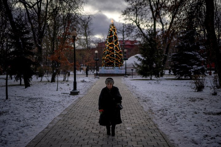 A woman walks near an illuminated Christmas tree, in Kyiv, amid Russia's attack on Ukraine December 12, 2024. REUTERS/Thomas Peter     TPX IMAGES OF THE DAY