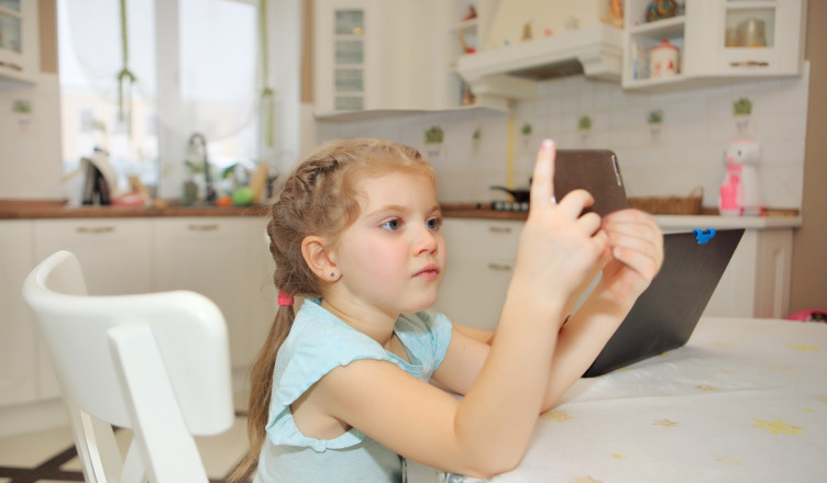 A,Young,Girl,Sits,At,The,Kitchen,Table,,Fully,Engaged